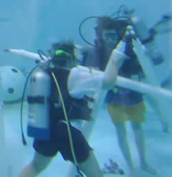 Wearing SCUBA gear, students build part of the space station truss system at the bottom of a 30 foot tank.